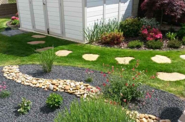 Jardin aménagé avec pelouse, pas japonais en pierre et massif de fleurs colorées