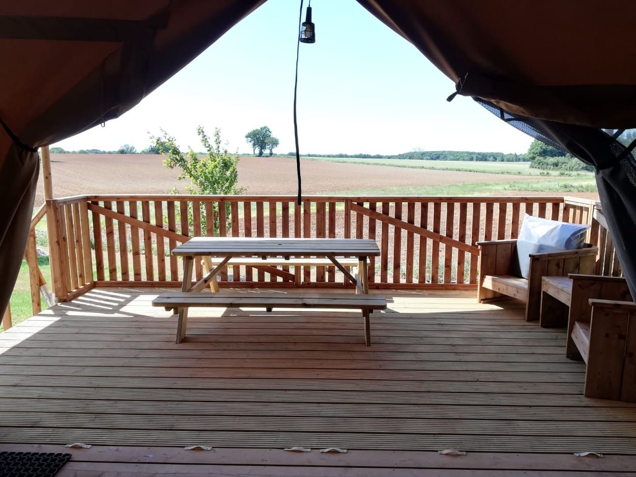 Aménagement paysager des toutes nouvelles tentes safari au village flottant de pressac réalisé au printemps 2020 - mb paysage prassac tente safari village flottant Terrasse en bois avec table pique-nique et fauteuils sous tente ouverte sur paysage rural