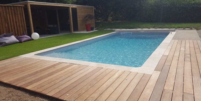 Piscine rectangulaire avec terrasse en bois et pelouse verte
