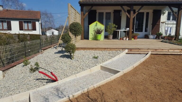 Aménagement paysager avec terrasse en bois, allée de pierres et espace gravillonné avec arbustes taillés
