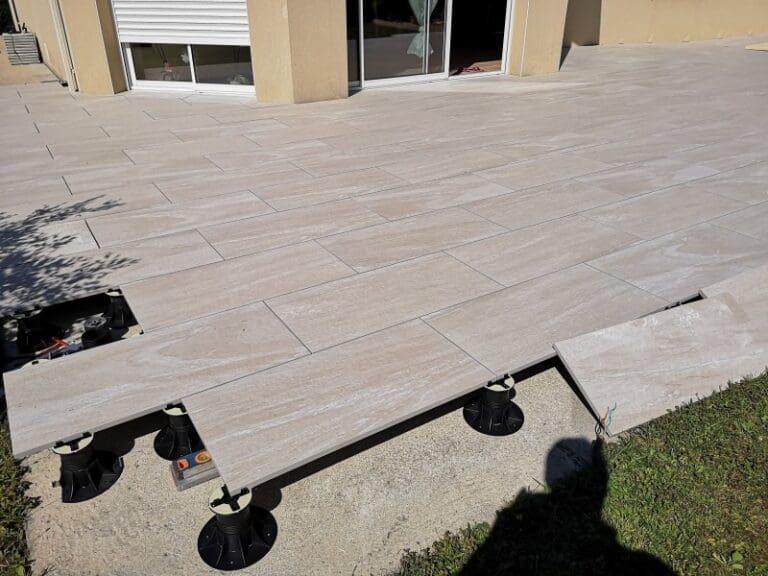 Terrasse en dalles beige clair posée sur plots réglables avec finitions autour de maison