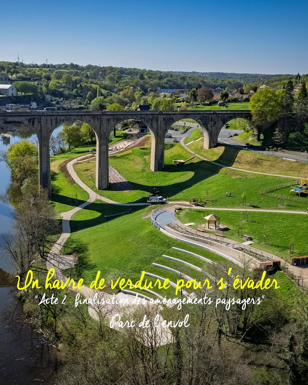 Parc verdoyant avec cheminements piétons sous un viaduc en pierre, vue aérienne au soleil