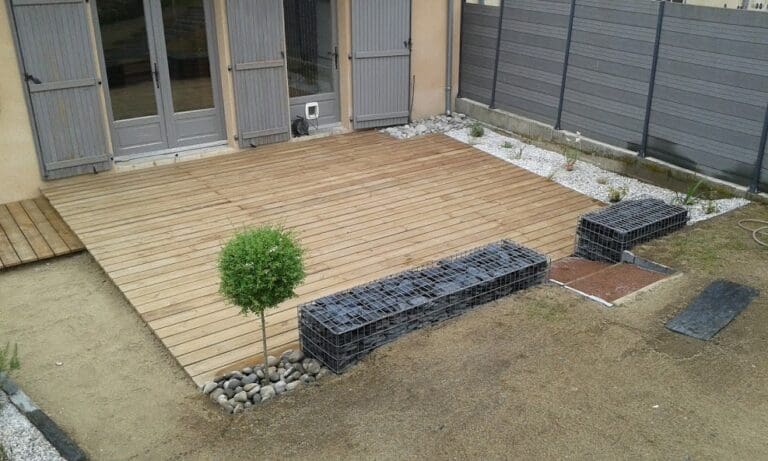 Terrasse bois aménagée avec arbre taillé et bordures de gabions remplis de pierres