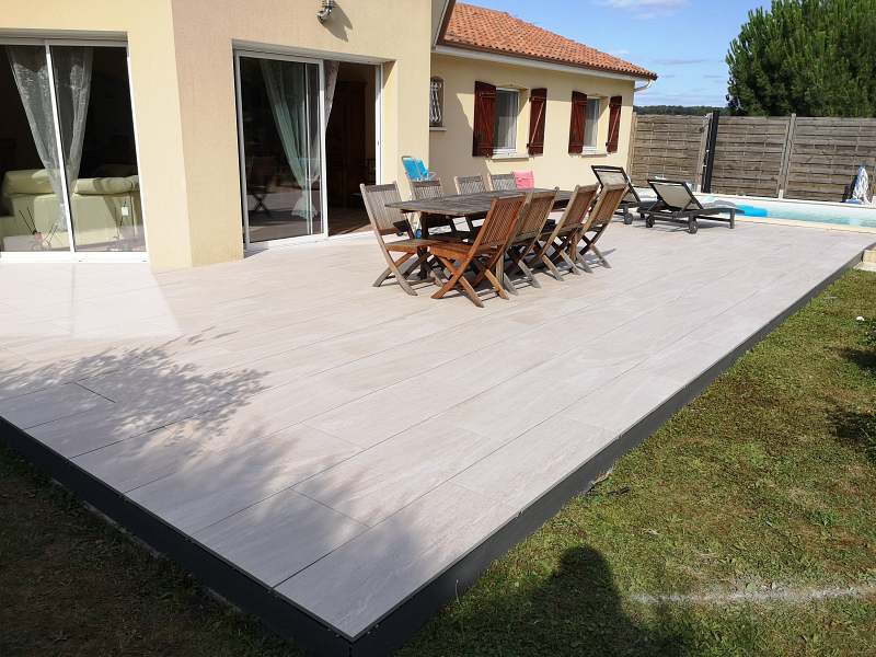 La terrasse sur plots - terrasse bois mb paysage Grande terrasse en dalles claires avec table et chaises en bois à côté d'une piscine