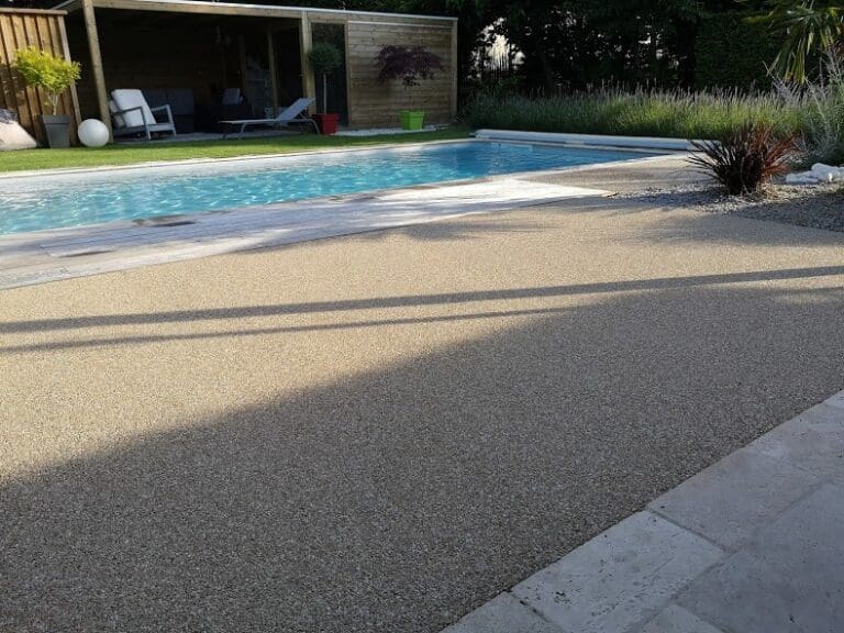 Piscine entourée d'une terrasse en gravier stabilisé avec jardin et salon de jardin