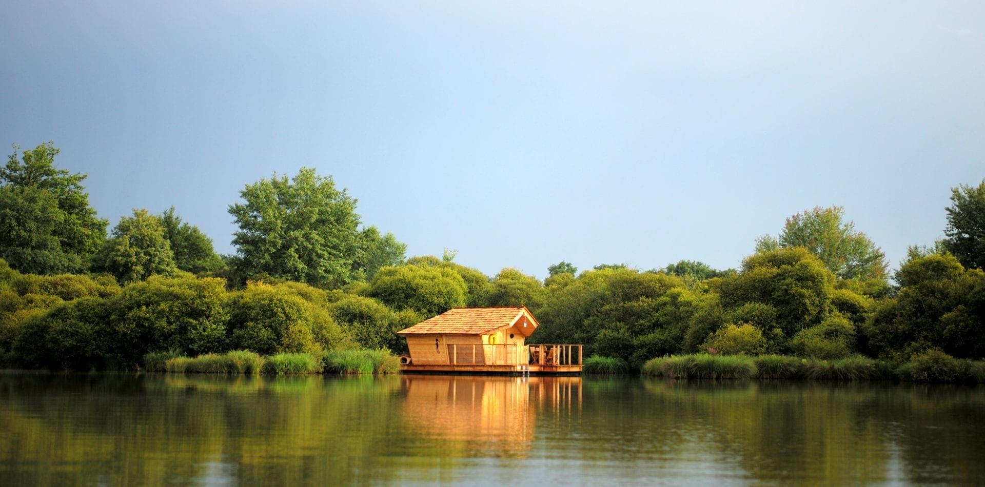 Cabane en bois flottant sur un plan d'eau devant des arbres verts
