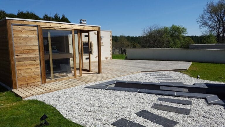 Aménagement extérieur avec terrasse en bois, spa et pavés sur gravier blanc