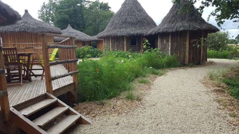 Petits chalets ronds en bois avec toits de chaume et chemin en gravier
