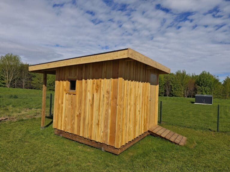 Petite cabane en bois avec une petite fenêtre et une rampe en bois sur pelouse verte