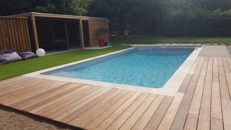 Piscine rectangulaire avec terrasse en bois et abri en bois dans un jardin
