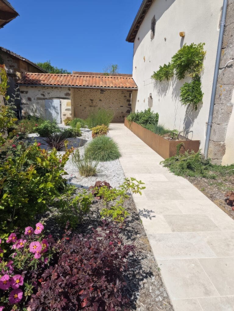 Allée dallée bordée de plantes et massifs dans un jardin paisible sous un ciel bleu