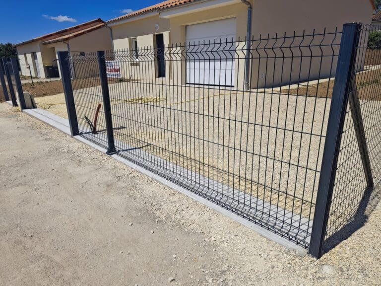 Clôture métallique noire avec cadre en acier devant une allée en gravier clair proche d'une maison moderne